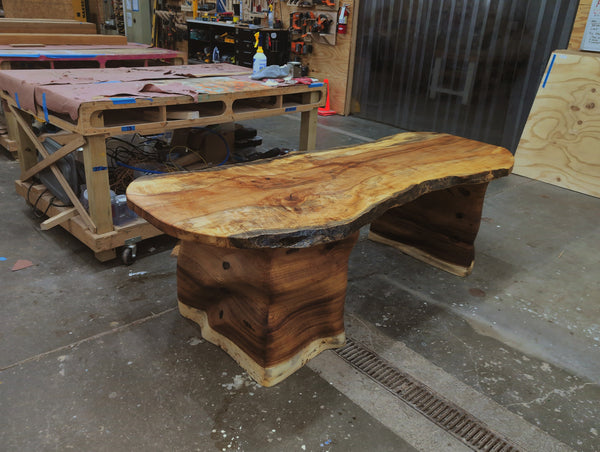 Custom solid wood desk base with CNC-machined 3D relief wrapping continuously across all four sides, BFW custom design.