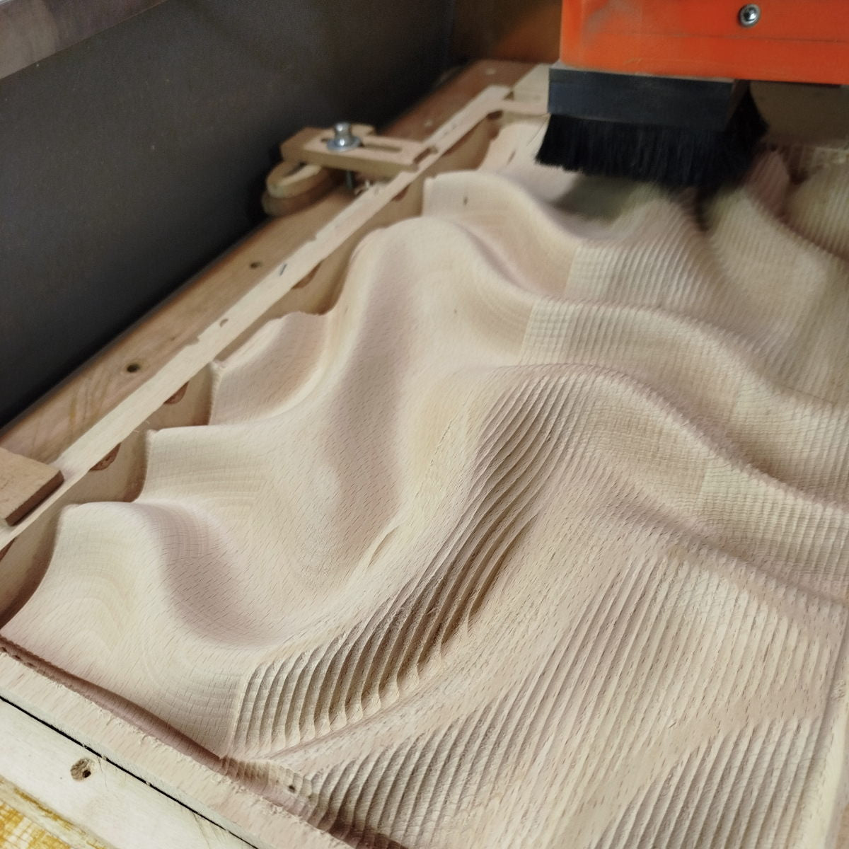 CNC router carving a 3D organic wave relief in wood, mid-cut showing toolpath precision and surface depth, BFW design WP9